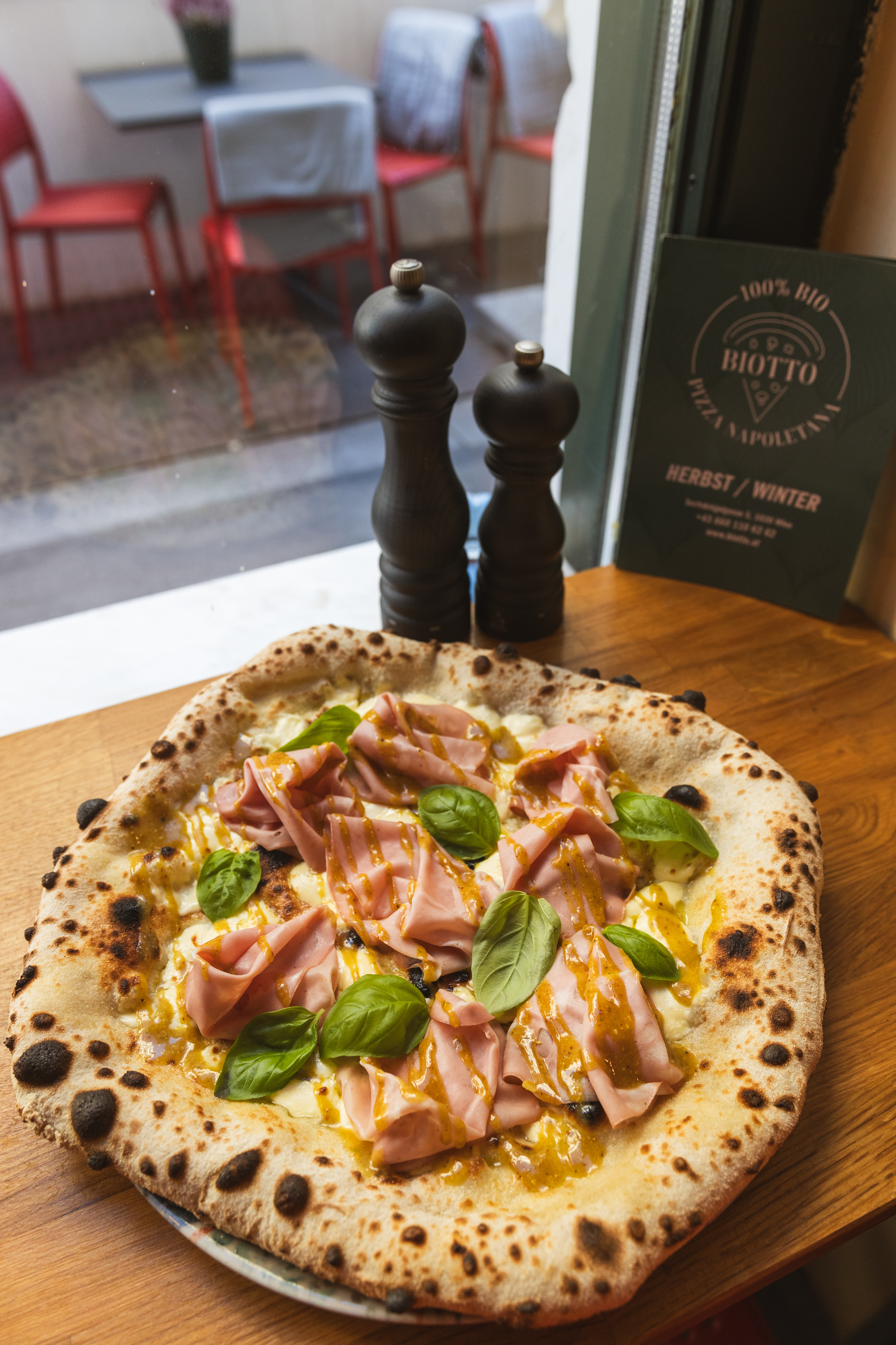 Pizza mit Mortadella, Pistazien-Pesto und Basilikum