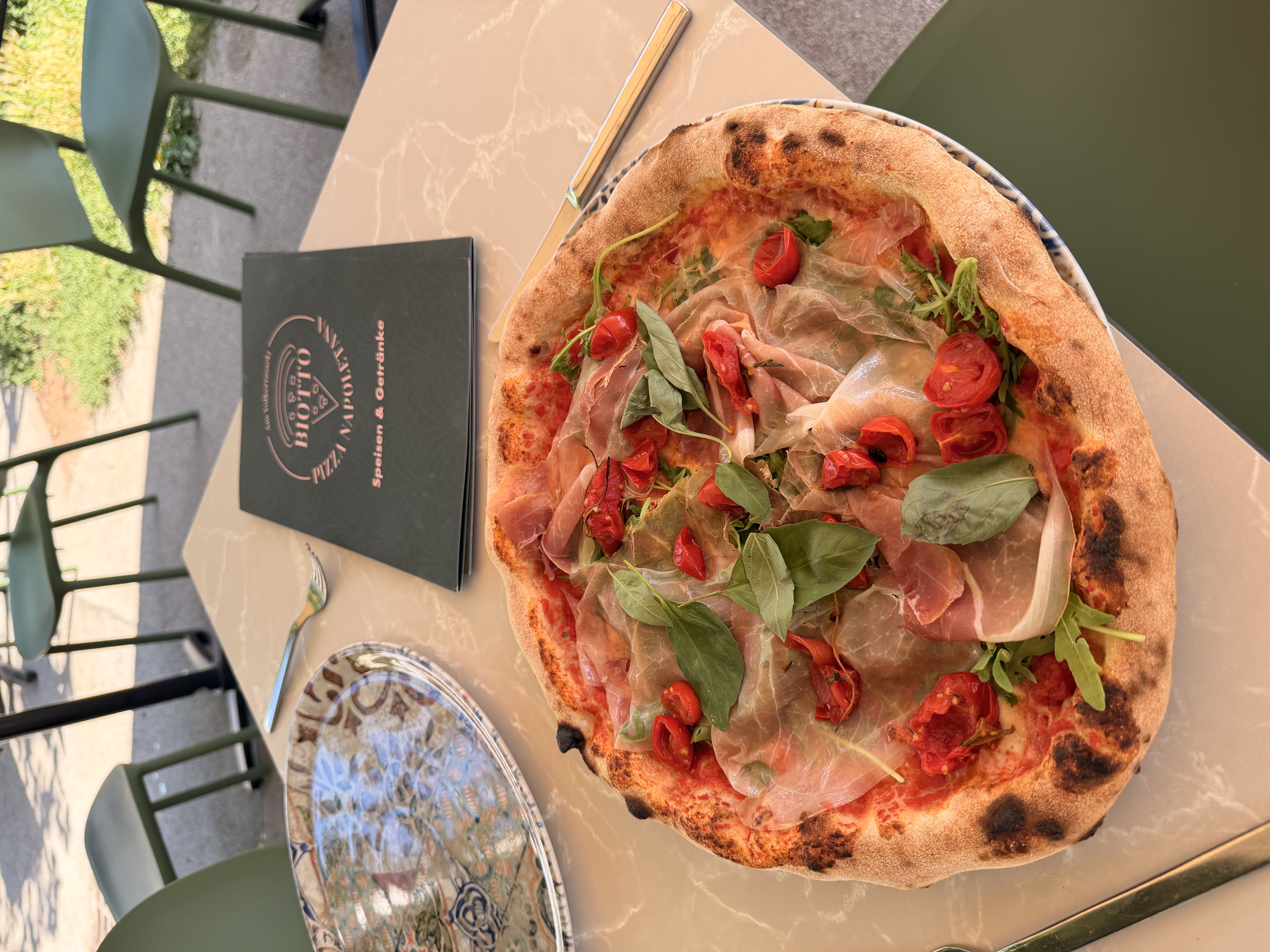 Pizza mit Parmaschinken, Kirschtomaten und Rucola